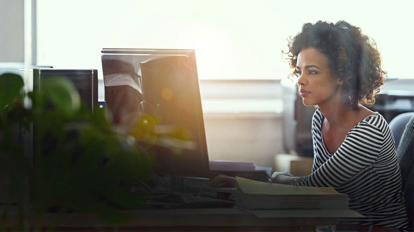 Woman sitting at a desk and looking at a computer.