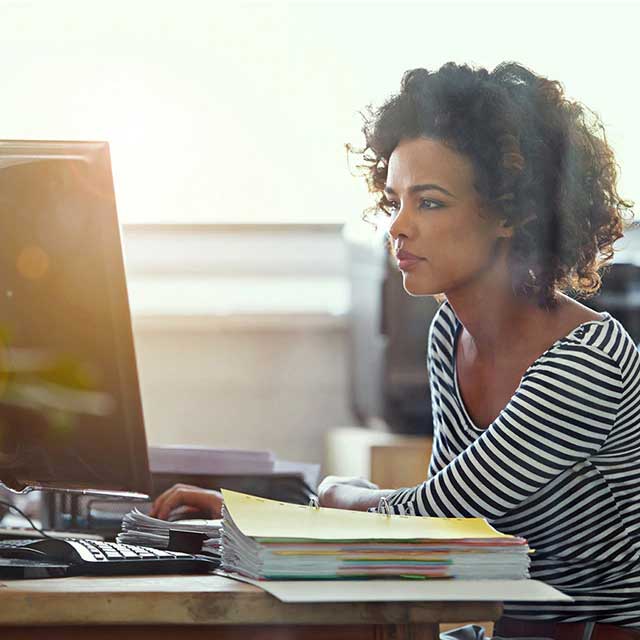 Woman sitting at a desk and looking at a computer.