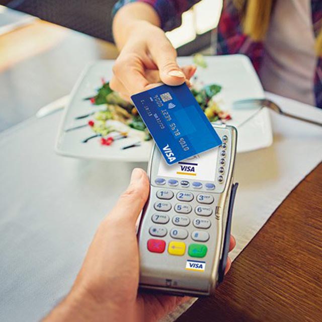 Contactless Visa card being used at a QSR