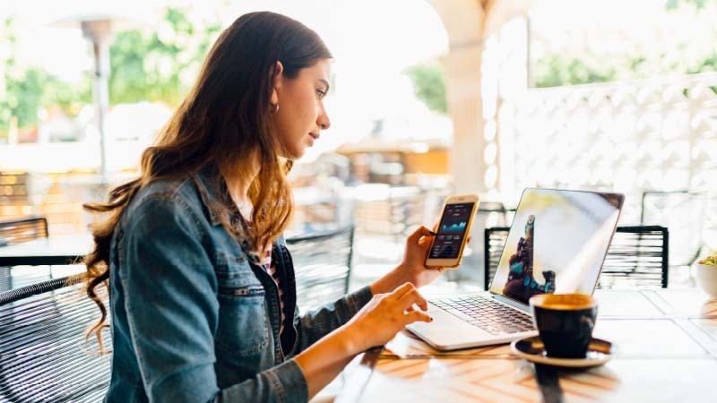 Mujer utilizando su celular y computadora